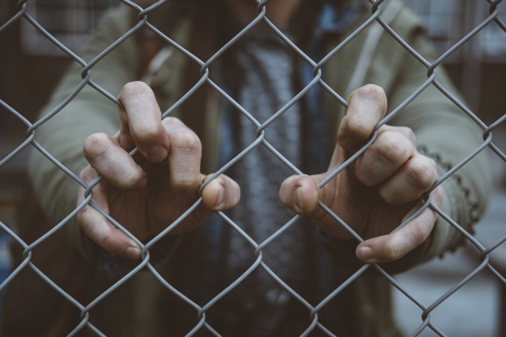 close-up of hand on chain-link fence